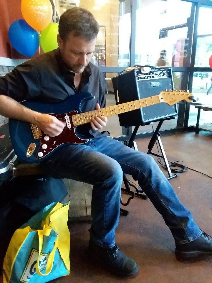 Benjamin Hoadley sitting down playing an electric guitar