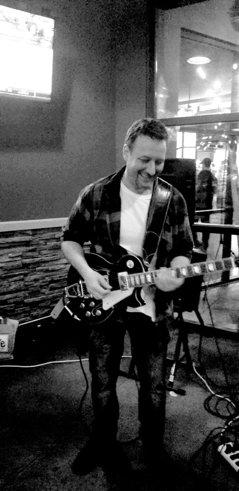 Benjamin Hoadley standing playing an electric guitar (Black and White)